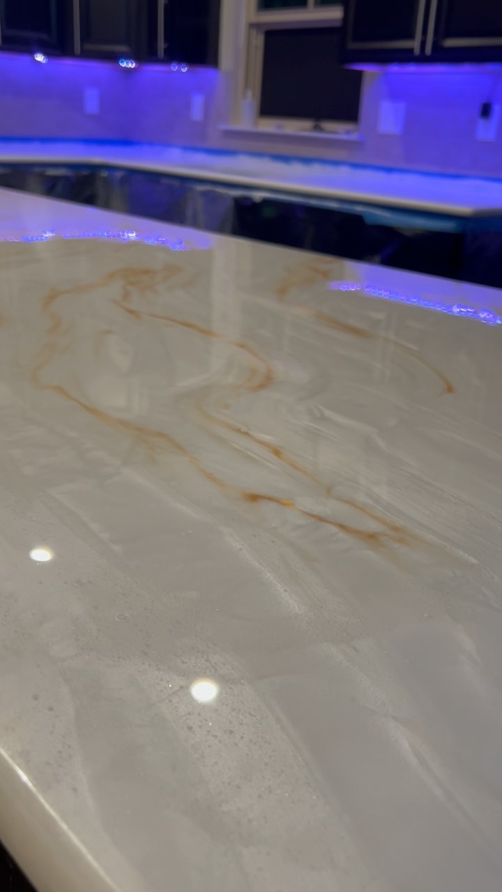 Pearl and gold epoxy kitchen counter beneath blue accent lighting, from the finished-project reel